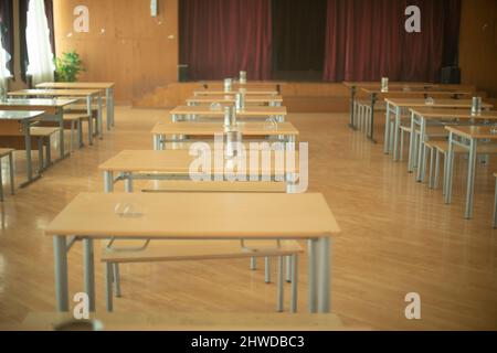 School canteen in Russia. Tables stand in row in hall. Place of public catering. Assembly hall in school. Desks and benches. Stock Photo