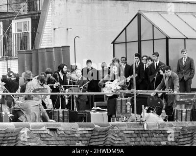 The Beatles perform a rooftop concert at Apple Headquarters, 3 Saville Row London on 30th January 1969. The performance was a part of filming for a documentary of the band rehearsing and recording the album Let It Be. The 42 minute session drew crowds to the street & adjoining rooftops. This was the band's final live performance before breaking up in April 1970. Performing on the roftop left to right: Ringo Starr, Paul McCartney, John Lennon and George Harrison. Stock Photo
