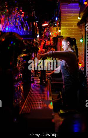 Female bartender prepares a drink while working in a bar. Stock Photo