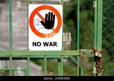 Gate closed with padlock and red sign with large black hand indicating to stop and great message NO WAR Stock Photo