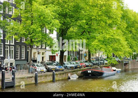 AMSTERDAM - AUGUST 2011: Famous canals of Amsterdam, Netherlands. Cars and bicycles parked on the embankments. Typical street view in Amsterdam, Holla Stock Photo