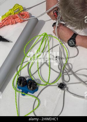 Close-up view of a sailor sets up a sports boat, set of ship equipment, ropes for management of the sailboat of different color, pulleys and ropes Stock Photo