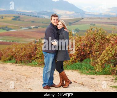 They are in their element. Portrait of a young couple standing together in the vineyards. Stock Photo