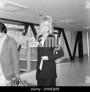 Goldie Hawn, American actress at London Heathrow Airport, Saturday 4th July 1970. Goldie and husband Gus Trikonis (holding carpet) are flying to their Los Angeles home. Stock Photo