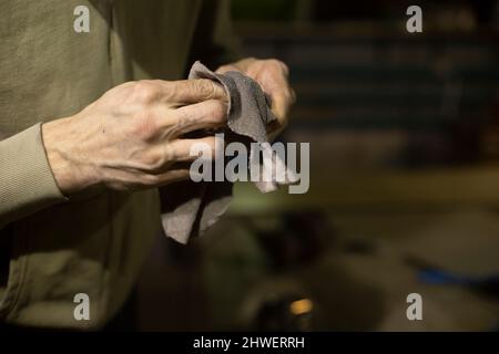 Wipe part with rag. Rag in his hands. Person cleans mechanism from dirt. Hands of man. Stock Photo