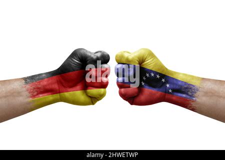 Two hands punch to each others on white background. Country flags painted fists, conflict crisis concept between germany and venezuela Stock Photo