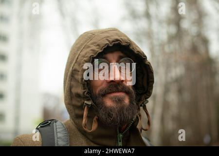 Guy with glasses. Man in hood. Man on street. Beard on his face. Stock Photo