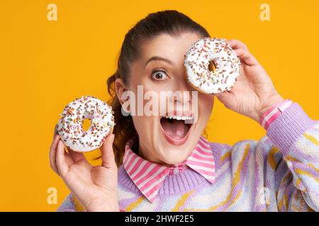 Young beautiful woman over yellow background with donuts Stock Photo