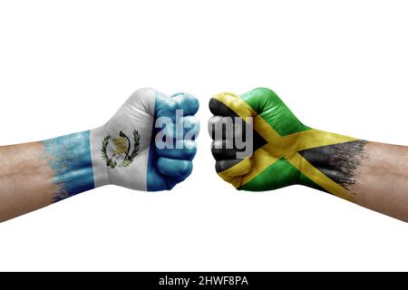 Two hands punch to each others on white background. Country flags painted fists, conflict crisis concept between guatemala and jamaica Stock Photo