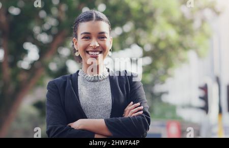 This city has been too good to my business. Cropped portrait of an attractive young businesswoman smiling while standing with her arms crossed Stock Photo