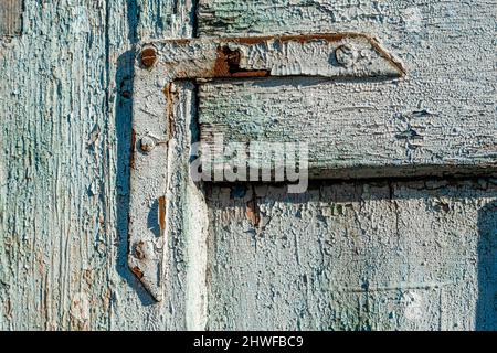 Blue paint on an old metal corner holder on wooden door with paint weathered Stock Photo