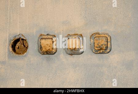Row of dirty badly painted plastic light switches on a wall with hole instead one of them. Concept- electricity, album cover Stock Photo