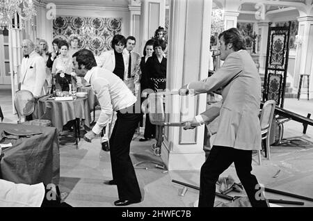 Roger Moore and Tony Curtis fight with each other on the set of The Persuaders! at Pinewood Film Studios, Iver, Bucks. Roger plays an English Lord, who meets Tony (playing a brash Brooklyn self made millionaire) and in this opening sequence they have a spectacular running fight across a restaurant. 11th August 1970. Stock Photo