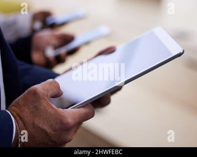 Our new brief just came in. Cropped shot of an unrecognizable group of businesspeople standing together in a circle and using technology. Stock Photo