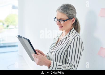 Completing tasks with ease and efficiency. Shot of a mature businesswoman using a digital tablet in an office. Stock Photo