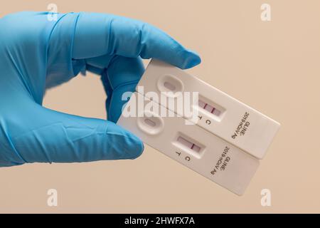 Doctor hand in glove hold Positive (2 red bars) and negative Result for coronavirus COVID-19 with test kit for viral disease. novel Lab card rapid tes Stock Photo