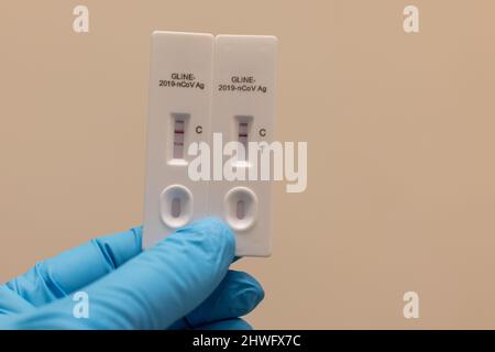 Doctor hand in glove hold Positive (2 red bars) and negative Result for coronavirus COVID-19 with test kit for viral disease. novel Lab card rapid tes Stock Photo