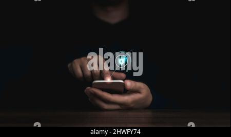 Shield lock button and personal information icons appeared while man's finger touching on smart mobile phone on dark background. Cyber security, data Stock Photo