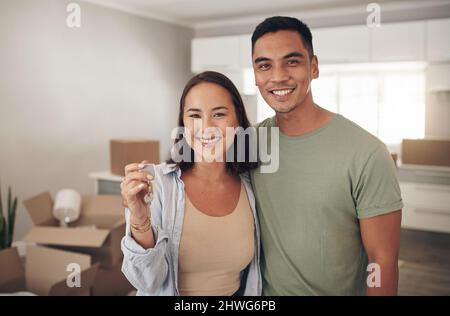 This is the key to a new beginning for us. Shot of a couple holding up the house key to their new home. Stock Photo