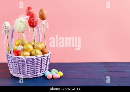 Easter colored eggs in a basket  pink background. Minimal concept. Card with copy space for text. Easter Decoration chick, rabbit Stock Photo