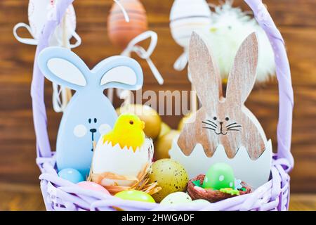 Easter eggs in the basket of wooden boards. yellow chicks on a  wooden background. The minimal concept. An Easter card with a copy of the place for th Stock Photo