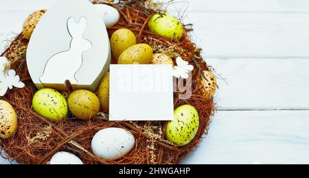 easter eggs, ribbons and nest on wooden  background mockup card with plants. invitation card with Stock Photo