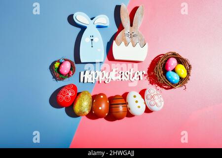 Happy Easter holiday background concept.Flat lay colorful bunny eggs  on modern beautiful grey-pink paper at office desk. Stock Photo