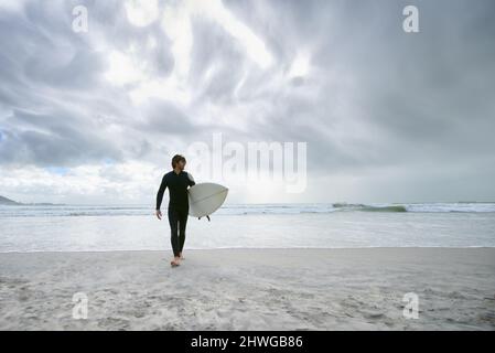 Hitting the beach. A surfer with his surfboard at the beach. Stock Photo