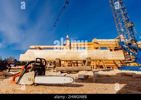 Concept of construction of wooden houses from solid logs, close-up chainsaw. Stock Photo