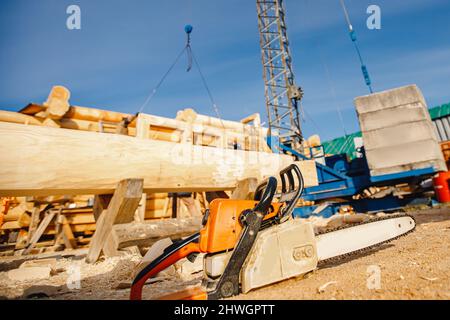 Concept of construction of wooden houses from solid logs, close-up chainsaw. Stock Photo