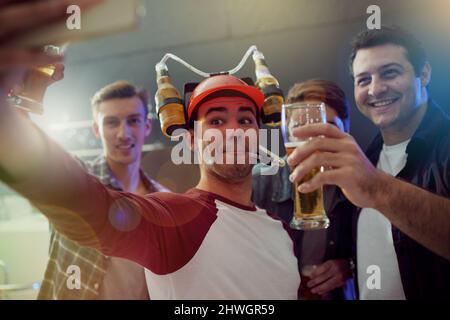 Snapping some party pics. Cropped shot of guys taking a selfie while drinking beer at a party. Stock Photo