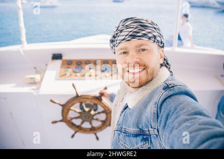 Tourist man on keffiyeh or arabic shawl driver captain of white luxury yacht making selfie. Concept boat rental in Arab Emirates, Egypt. Stock Photo