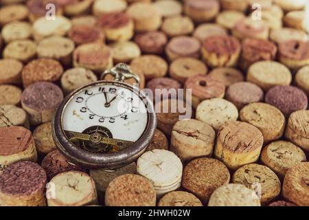 Antique pocket watch on old Used corks plugs from various types of wine on dark background Stock Photo