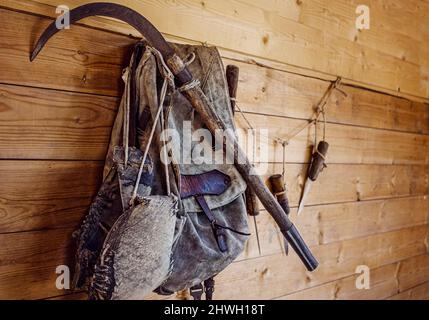old fishing tackle and a backpack hanging on a plank wall Stock Photo