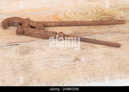 An old rusty iron adjustable spanner on wooden background. Stock Photo