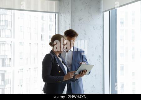 Focused two middle aged colleagues using digital tablet. Stock Photo