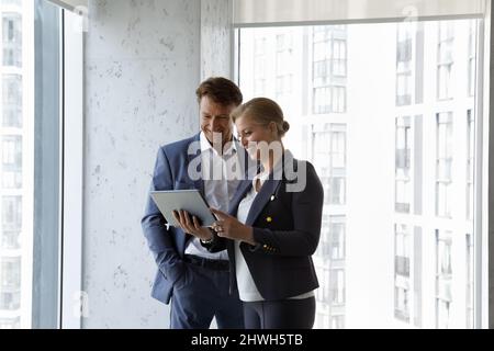 Happy middle aged colleagues using digital tablet. Stock Photo