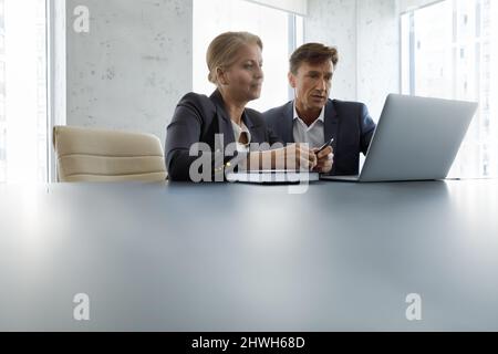 Focused middle aged colleagues working on laptop. Stock Photo