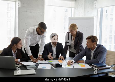 Group of focused young serious multiracial colleagues doing paperwork. Stock Photo