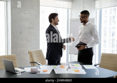 Happy two diverse businessmen making agreement in office. Stock Photo
