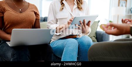 Taking digital notes as the presentation goes. Closeup shot of two unrecognisable businesswomen using a laptop and digital tablet during a meeting in Stock Photo