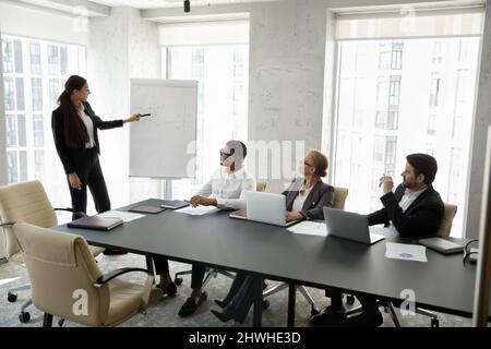 Young female speaker giving educational lecture to business people. Stock Photo