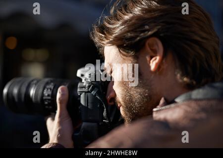 Photography is my passion. Shot of a handsome young photographer at work in the city. Stock Photo