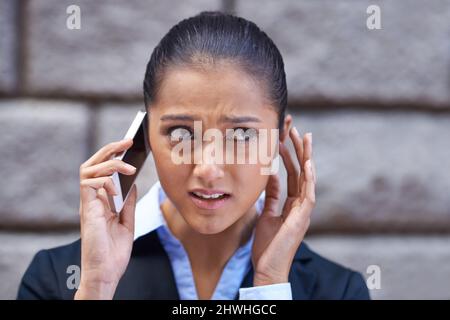 I cant quite hear you. A shot of a young businesswoman having trouble hearing on her cellphone. Stock Photo