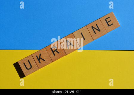Ukraine, word in wooden alphabet letters isolated on blue and yellow background, national flag colours Stock Photo