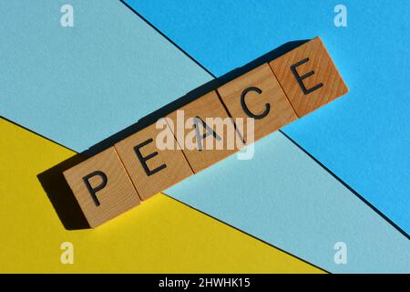 Peace, word in wooden alphabet letters isolated on blue and yellow background Stock Photo