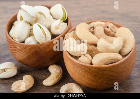 Cashew and pistachio in shell nuts in bowl on wooden table. Stock Photo