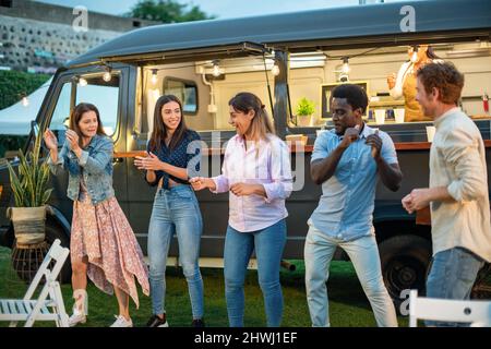 Happy diverse friends having fun near van Stock Photo
