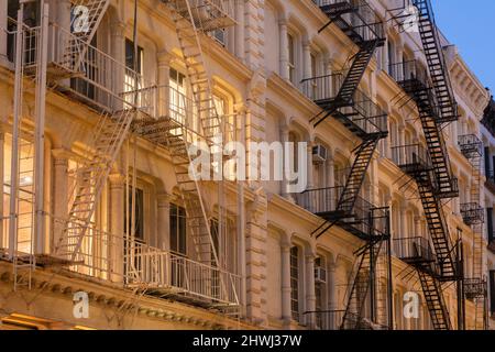 Facades of Soho loft buildings with fire escapes at dusk. Lower Manhattan, New York City Stock Photo