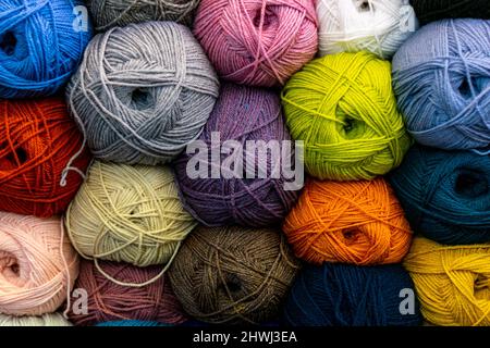 Many wool yarns in bright colours stacked on the shelf in store, multi color wool balls for knitting warm handmade clothing and accessories. Popular Stock Photo